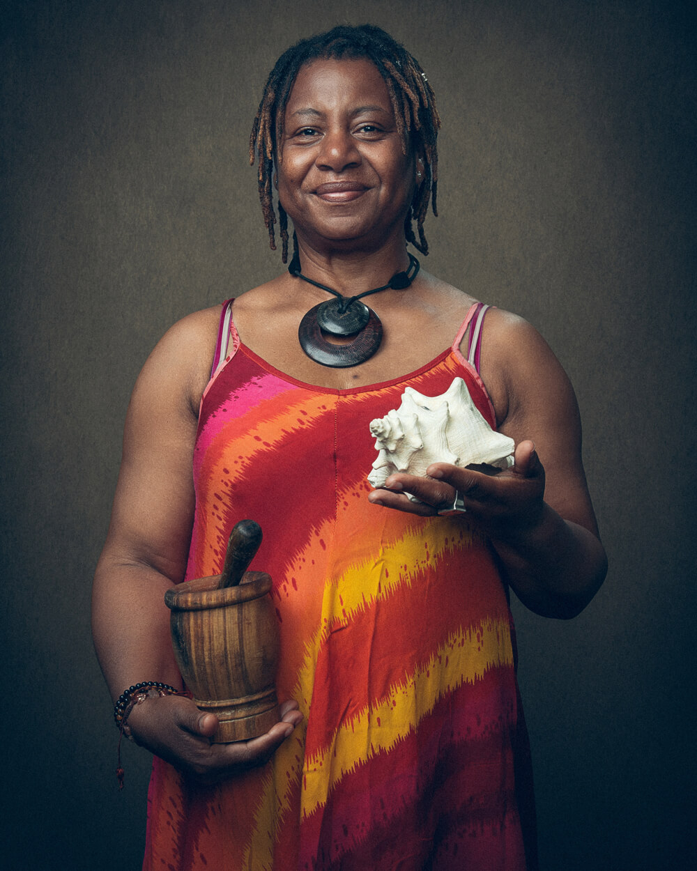 A portrait photo of April Manderson holding a pestle and mortar and a shell